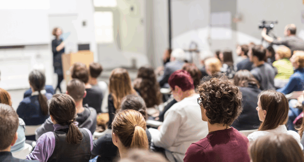 Speaker giving presentation in a university lecture hall.