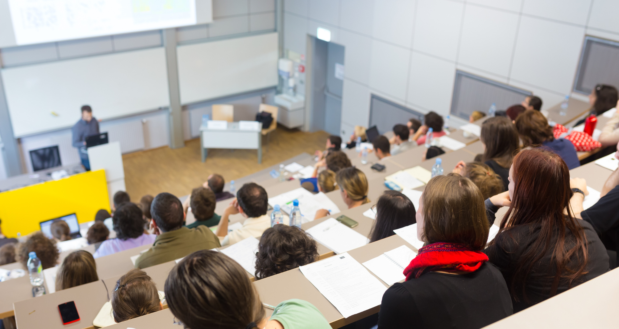 Speaker giving presentation in a university lecture hall.